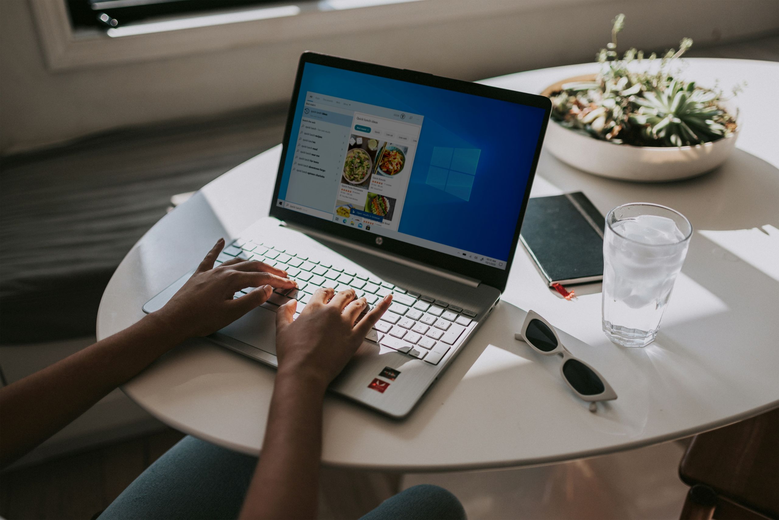 Close up of hands typing on a laptop showing Windows UI.