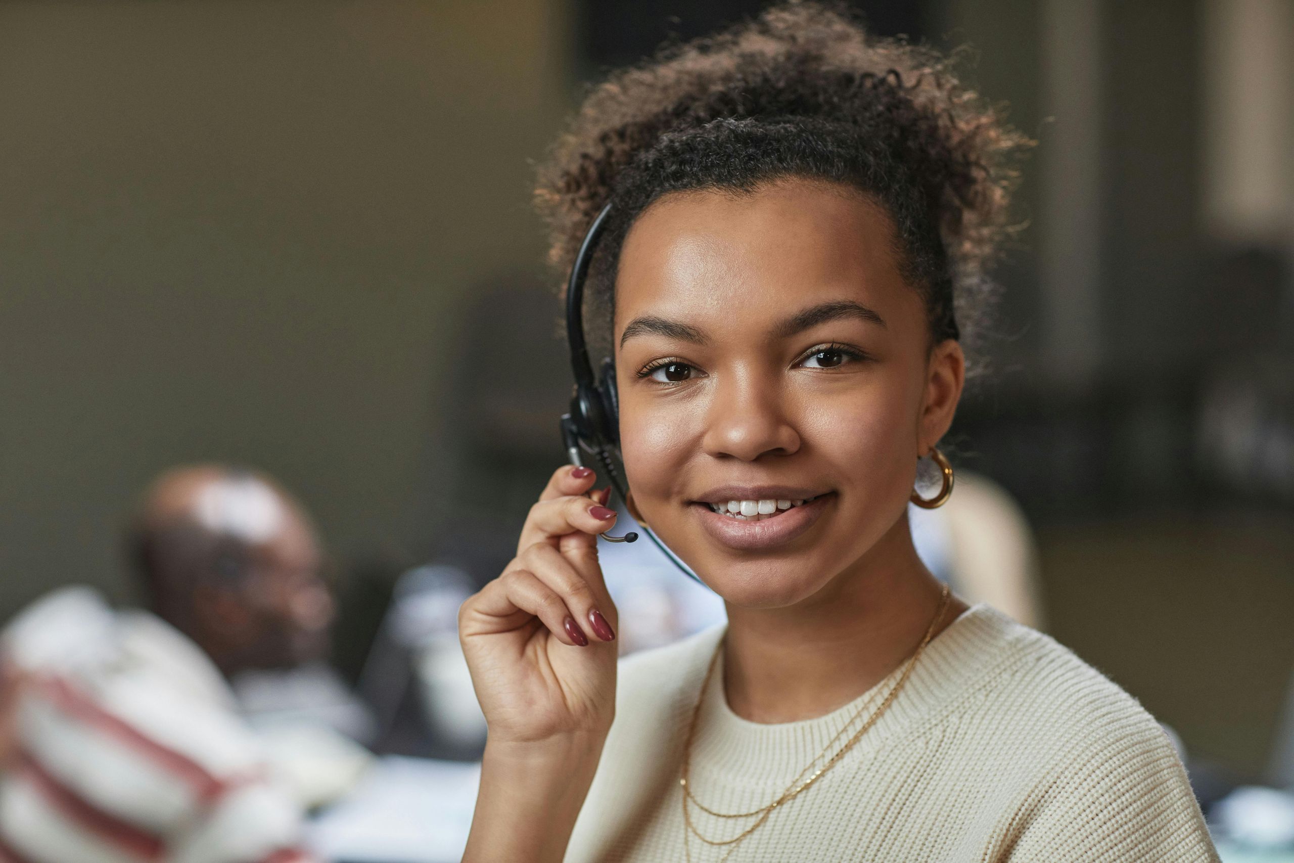 IT professional wearing headphones and a microphone smiling at the camera.