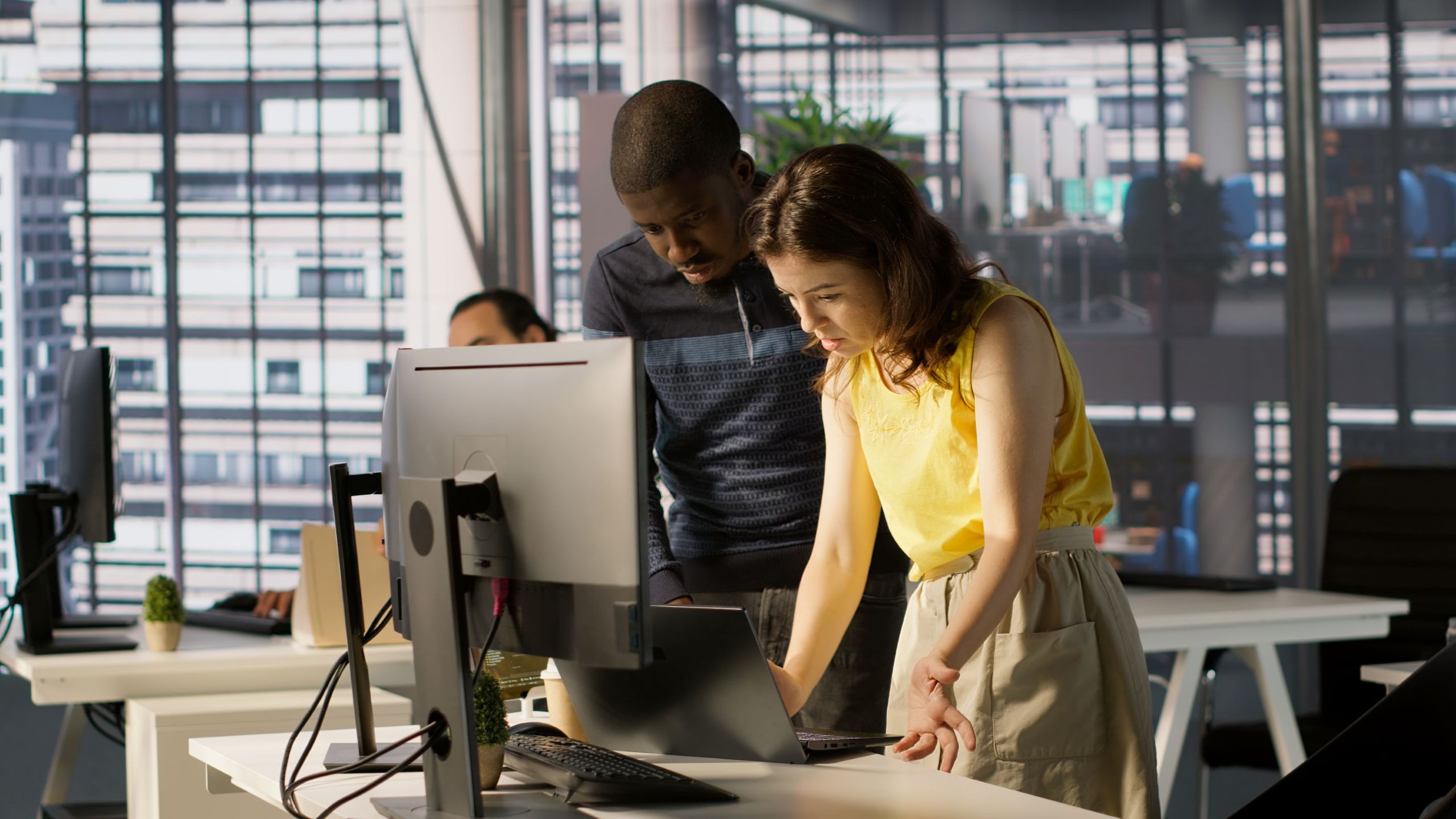 Two colleagues in front of a computer having discussion.