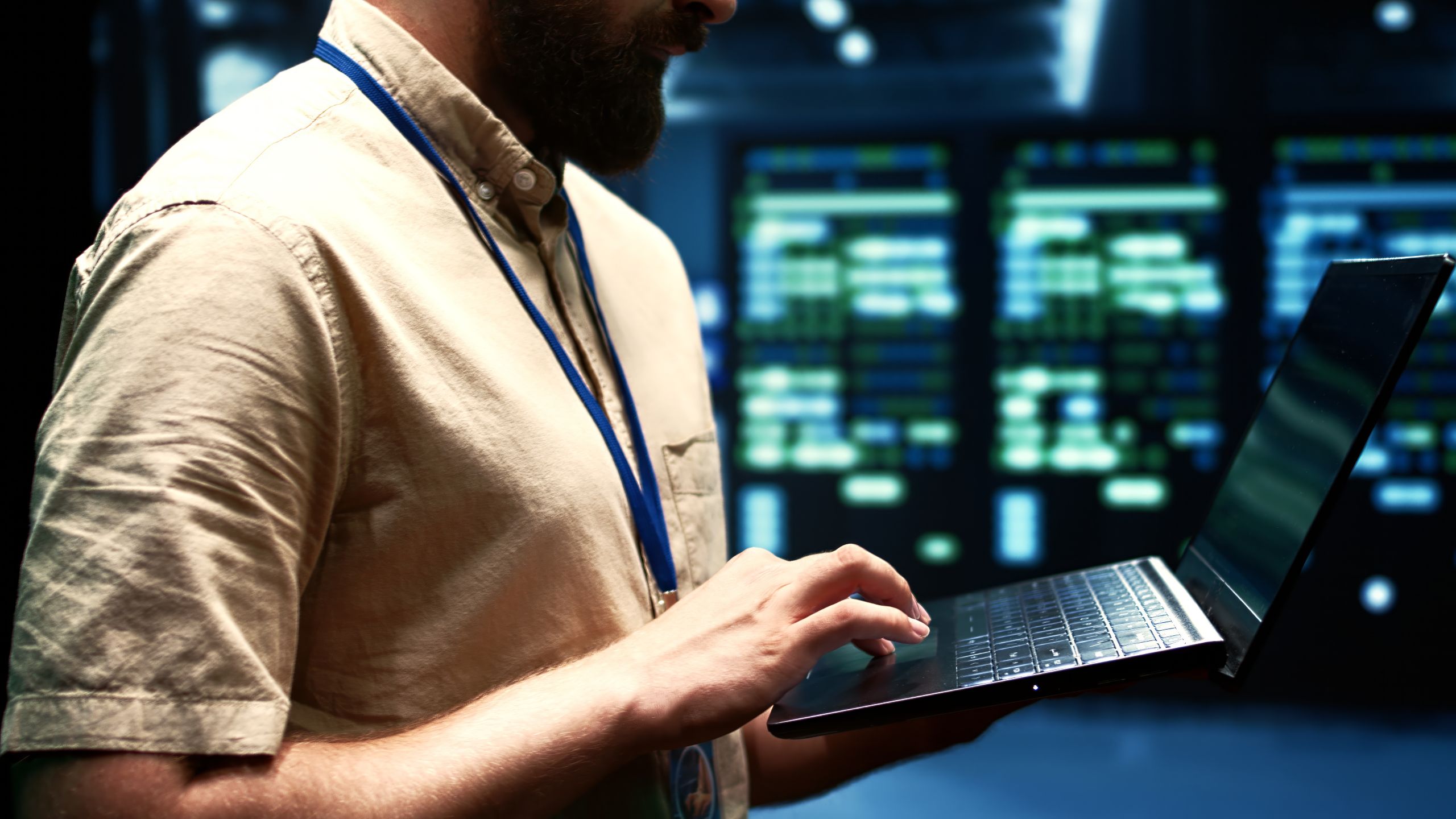 Close up of man holding a laptop inside a data center.